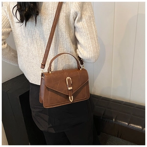 Detail of vintage brown shoulder bag with geometric stitching and gold U-shaped buckle