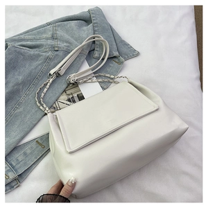 Detail of silver chain strap on a white leather tote bag with flap closure design