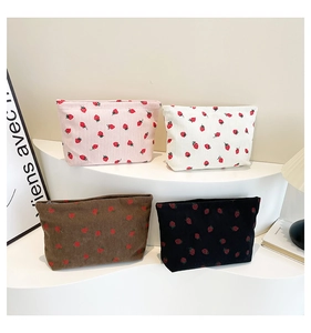 Detail of corduroy strawberry print bags showing soft texture and zip closure