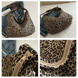 Detail of leopard print canvas hobo bag with gold zipper and wide strap on white fabric
