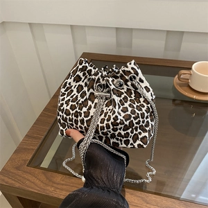 Stylish leopard print drawstring bucket bag with silver metal chain on a wooden surface