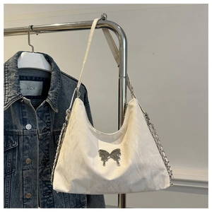 Detail of white textured shoulder bag featuring silver butterfly buckle and chain strap