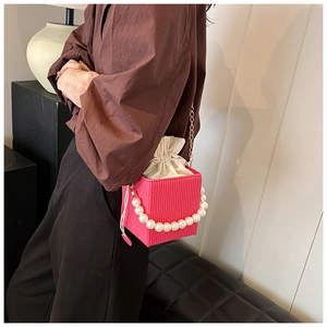 Detail of a bright pink cube bucket bag with large pearl handle and gold chain strap