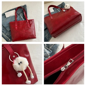 Detail view of burgundy tote bag with silver rivets and white plush monster charm
