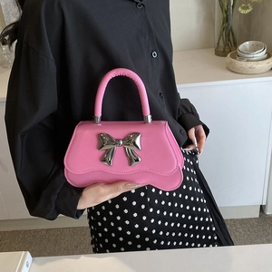 Sac à main carré rose avec grand nœud en métal argenté et base ondulée unique