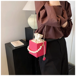 Detail of rose pink bucket bag with pearl handle, metal chain and drawstring closure