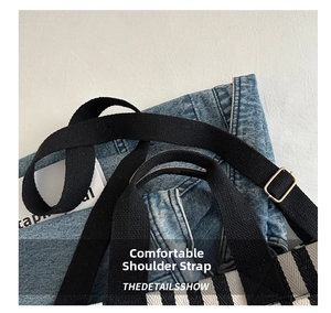 Detailed view of adjustable wide woven shoulder strap and metal buckle on canvas tote bag