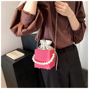 Detail of pink cube bucket bag with pearl handle, chain strap, and drawstring closure