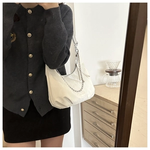 Detail of white pleated shoulder bag featuring a metallic chain and adjustable strap