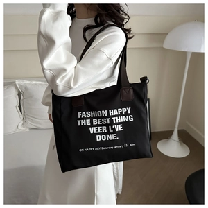 Close-up of minimalist black canvas tote bag with white text print and leather accents