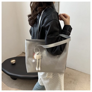 Detail of silver metallic tote bag with white plush charm and fashion text engraving