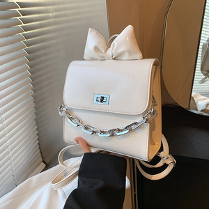 White glossy patent leather backpack featuring a large bow and silver chain strap details