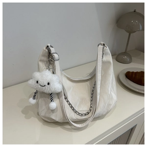 Dettaglio borsa a spalla bianca a pieghe con catena d'argento e ciondolo a nuvola soffice