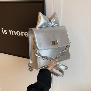 Y2K style silver metallic mini backpack with large bow detail and metal chain accent