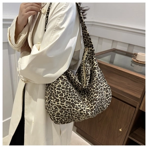 Close-up of leopard print canvas tote bag with zipper closure shown on a model