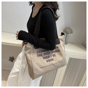 Detail view of large canvas tote bag showing wide shoulder strap and printed text design