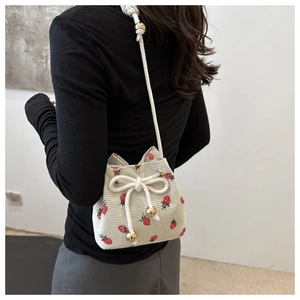 Close-up of strawberry print corduroy bucket bag with drawstring and gold metal bead