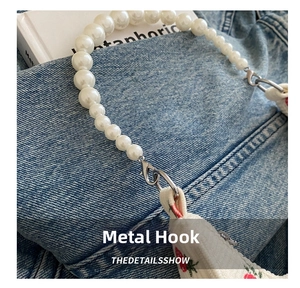 Detailed close-up of durable metal lobster hooks and white pearl strap on corduroy bag