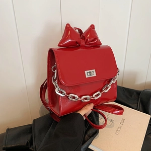 Red patent leather backpack with oversized bow and chunky silver chain accent