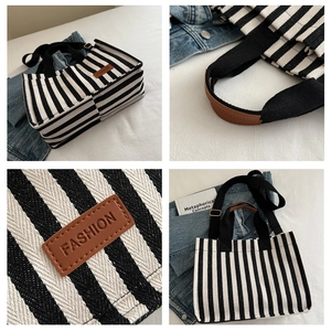 Detail of striped canvas tote with black woven handles and brown leather logo patch