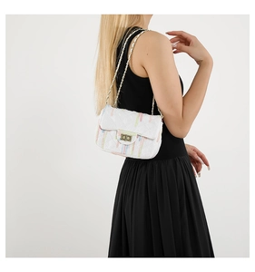Detail of tweed striped crossbody bag with gold chain strap and quilted texture