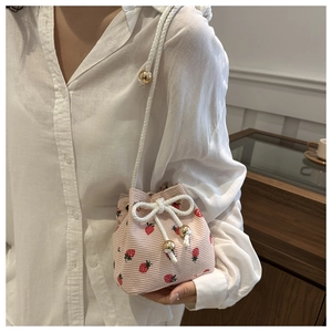 Detail of pink corduroy bucket bag featuring strawberry prints and white drawstring cord