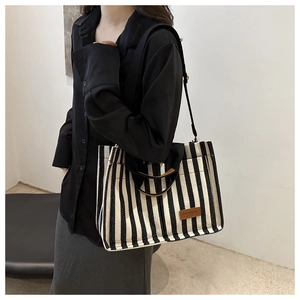 Detail shot of black and white striped canvas tote bag with fashion leather tag