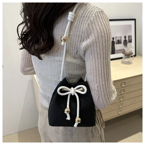 Detail of black woven bucket bag with cotton rope drawstring and gold bead accents