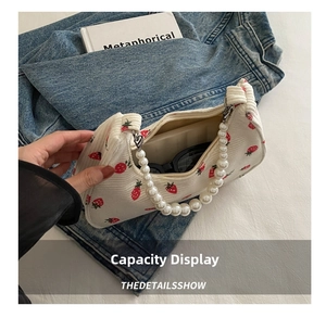 Detail of white corduroy strawberry bag with pearl handle showing inner storage capacity