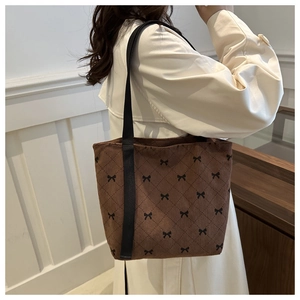 Détail du sac cabas en velours côtelé marron avec motifs de nœuds noirs et bandoulière