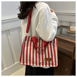 Détail du sac cabas à rayures rouges et blanches avec logo en cuir porté en mode décontracté