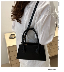 Detailed view of black pebbled leather texture on a minimalist tote bag with gold buckle