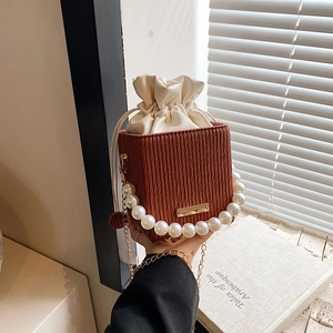 Brown pleated bucket bag with large pearl handle and gold chain shoulder strap