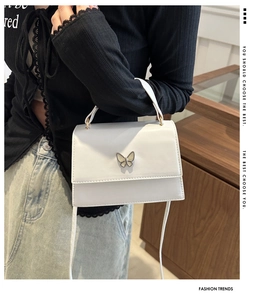 Close-up of elegant white square handbag with decorative butterfly buckle and handle