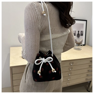 Detail of strawberry corduroy bucket bag showing velvet texture and gold metal accents