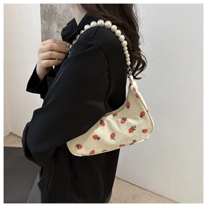 Detail of cream corduroy shoulder bag with red strawberry print and pearl bead strap