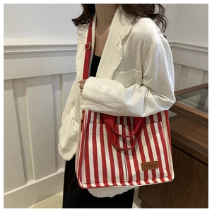 Detail of red and white striped canvas tote with adjustable strap and leather patch
