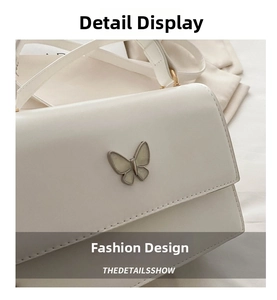 Close-up of white leather handbag featuring a polished silver butterfly metal clasp