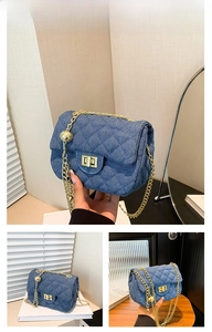 Detail der dunkelblauen Denim-Stepptasche mit goldener Kette und Drehverschluss