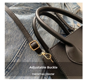Detail of black lychee grain leather handbag with gold hardware and curved stitching