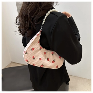 Close-up of pink corduroy shoulder bag with strawberry print and pearl beaded strap