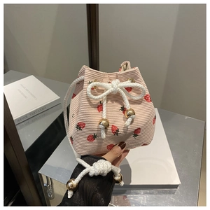 Detail of pink corduroy bucket bag featuring red strawberry prints and drawstring closure