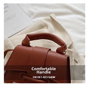 Close-up of brown lychee grain leather texture and metallic buckle on handbag