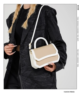 Detail view of a beige patchwork crossbody bag shown on a model in a black suit