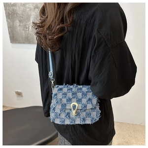 Sac bandoulière en jean bleu à carreaux avec boucle dorée porté par un mannequin