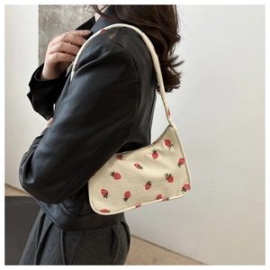 Détail du sac sous le bras en velours côtelé à imprimé fraises porté par un mannequin