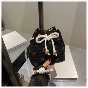 Detail of strawberry print corduroy bucket bag with woven drawstring and gold metal bead