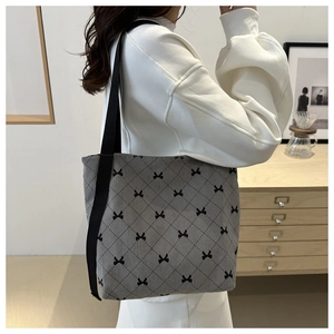 Détail du sac cabas en velours côtelé gris avec motif matelassé et nœuds noirs