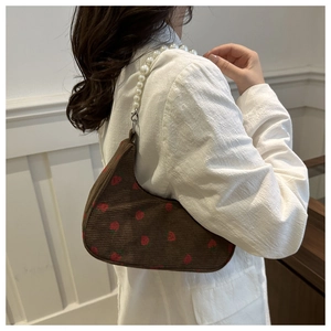 Detail of brown corduroy shoulder bag with strawberry print and pearl bead strap