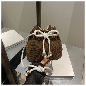 Detail of brown corduroy bucket bag with strawberry embroidery and gold bead accents